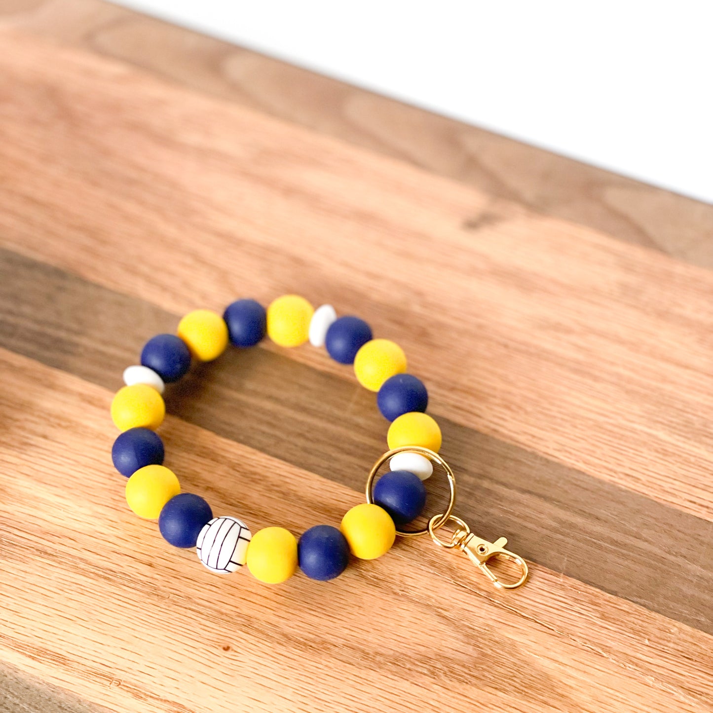 Silicone beaded wristlet keychain blue yellow beads with volleyball print bead laying on flat surface